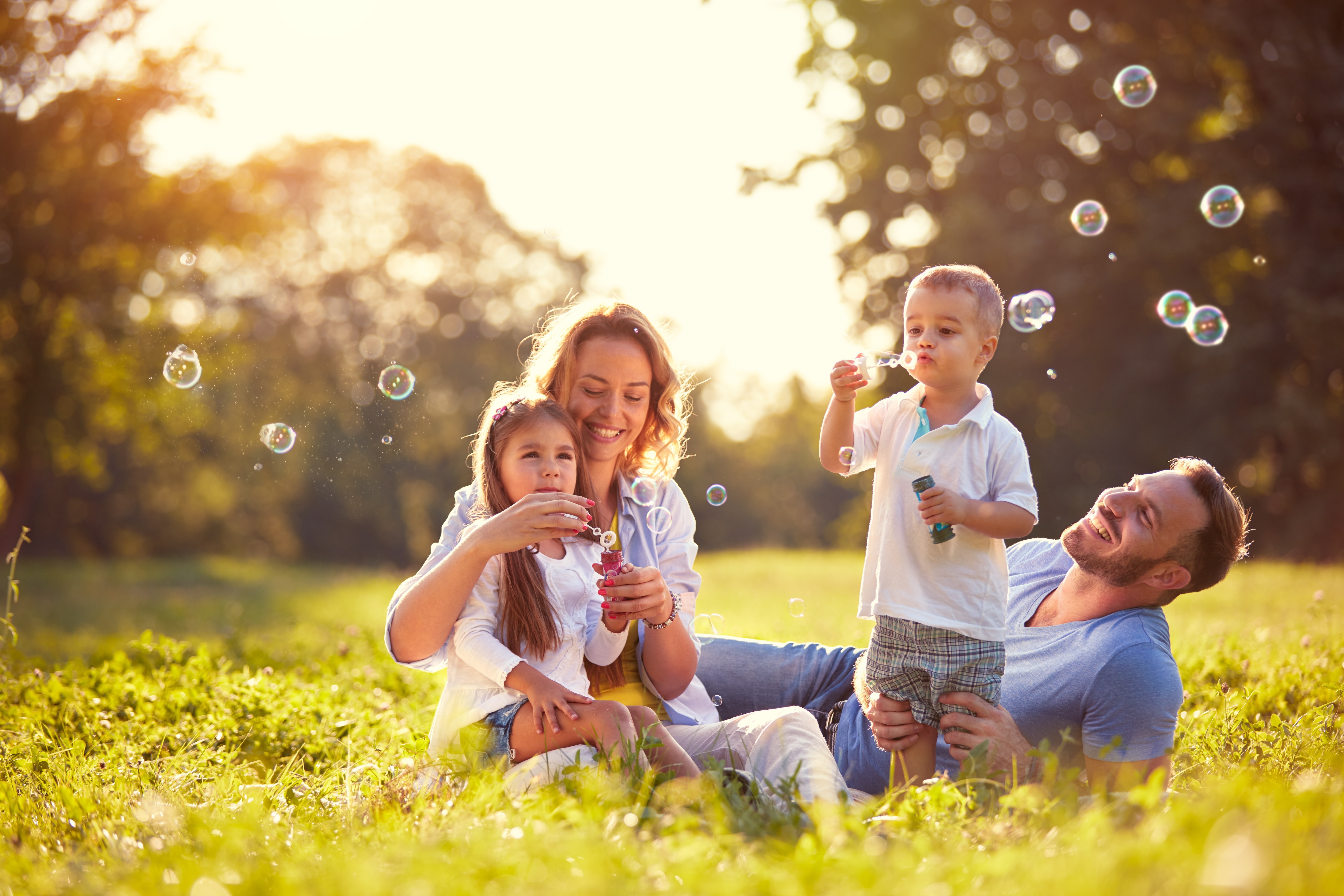 Family in the grass blowing bubbles stock image