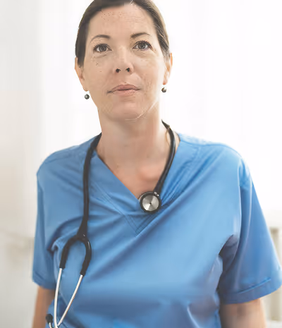 Female healthcare professional wearing blue scrubs and a stethoscope.