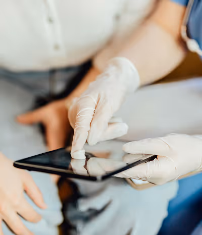 Person wearing white gloves pointing at a tablet screen held by another person.