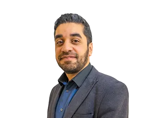 Man with dark hair and beard wearing a dark blazer and blue shirt, smiling slightly.