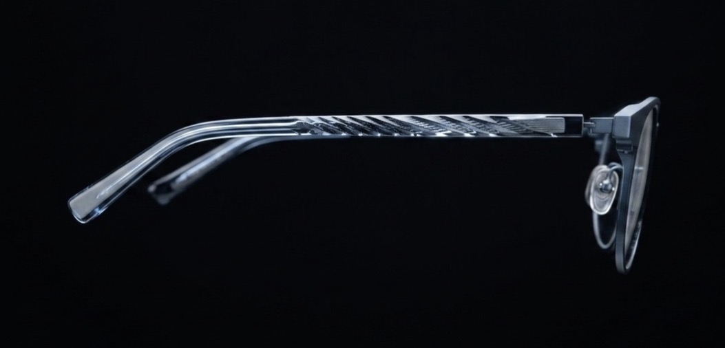 Side view of sleek prismara ergonomic loupes with transparent temple featuring a textured pattern against black background.