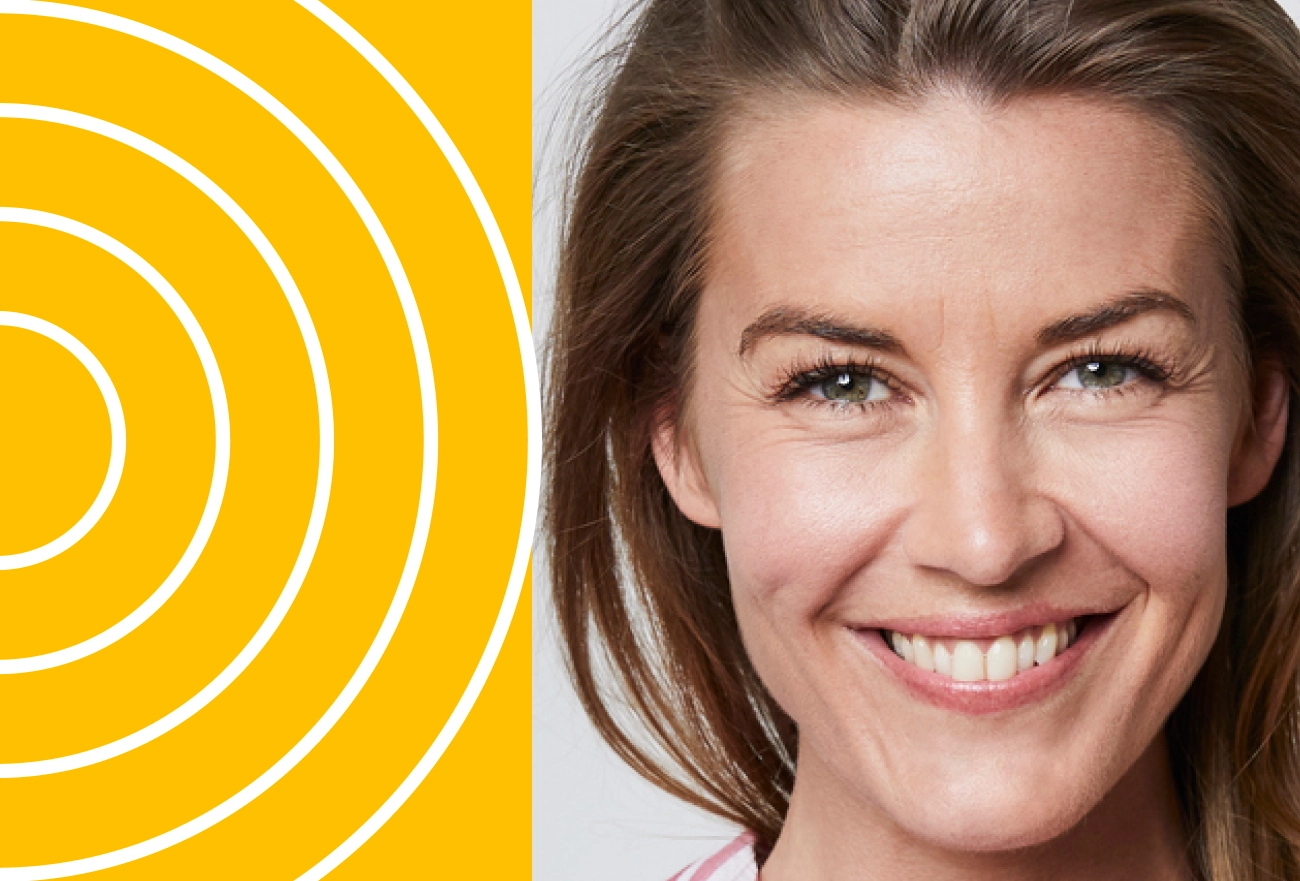 Smiling woman with green eyes beside white concentric circles on yellow background