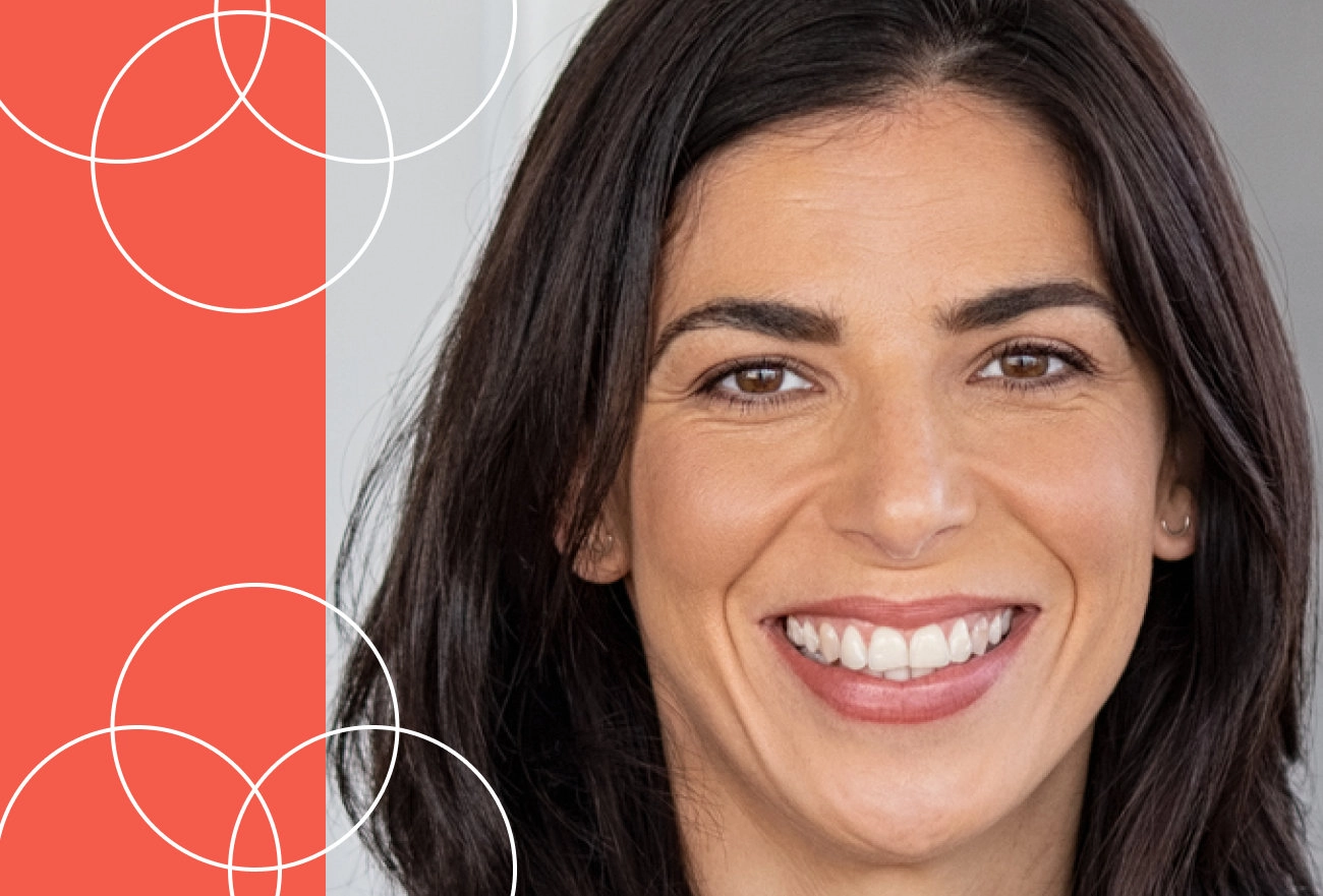 Woman with dark hair smiling next to red and gray background with white circular geometric shapes