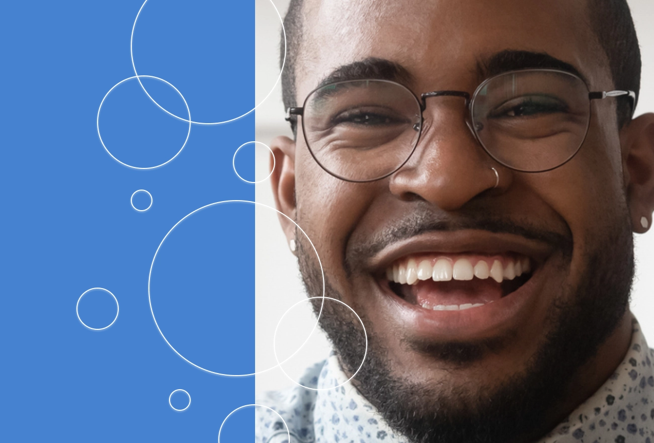 Man wearing round glasses smiling next to blue background with white circular geometric design