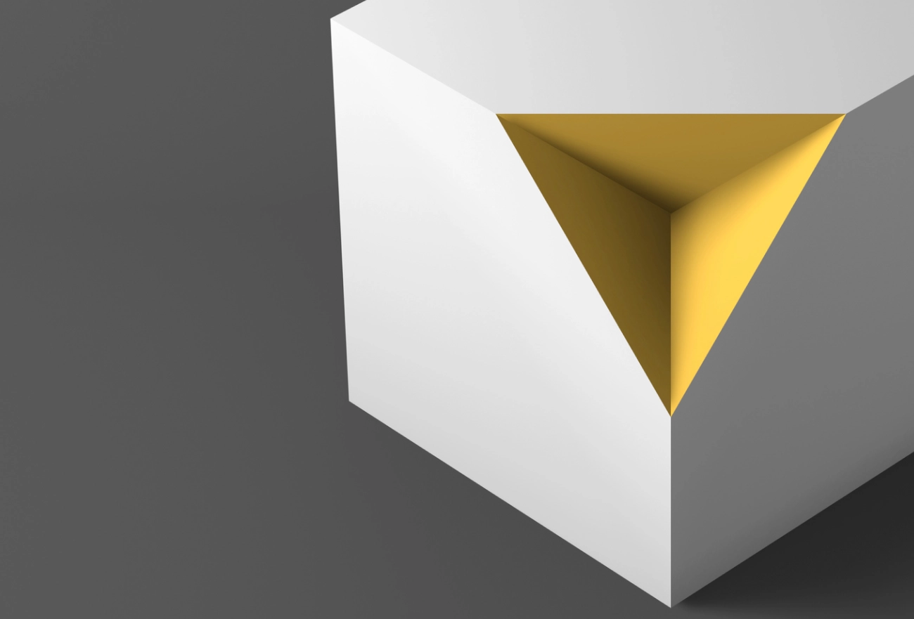 3D white cube with yellow triangular cutout on right side against gray background