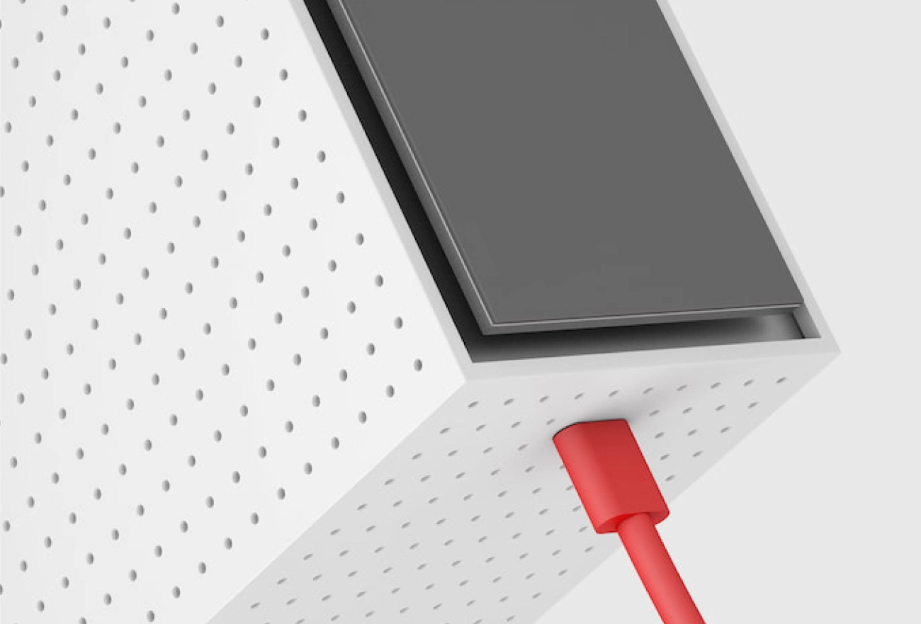 Tablet device with dark screen mounted on white perforated surface with red cable connector