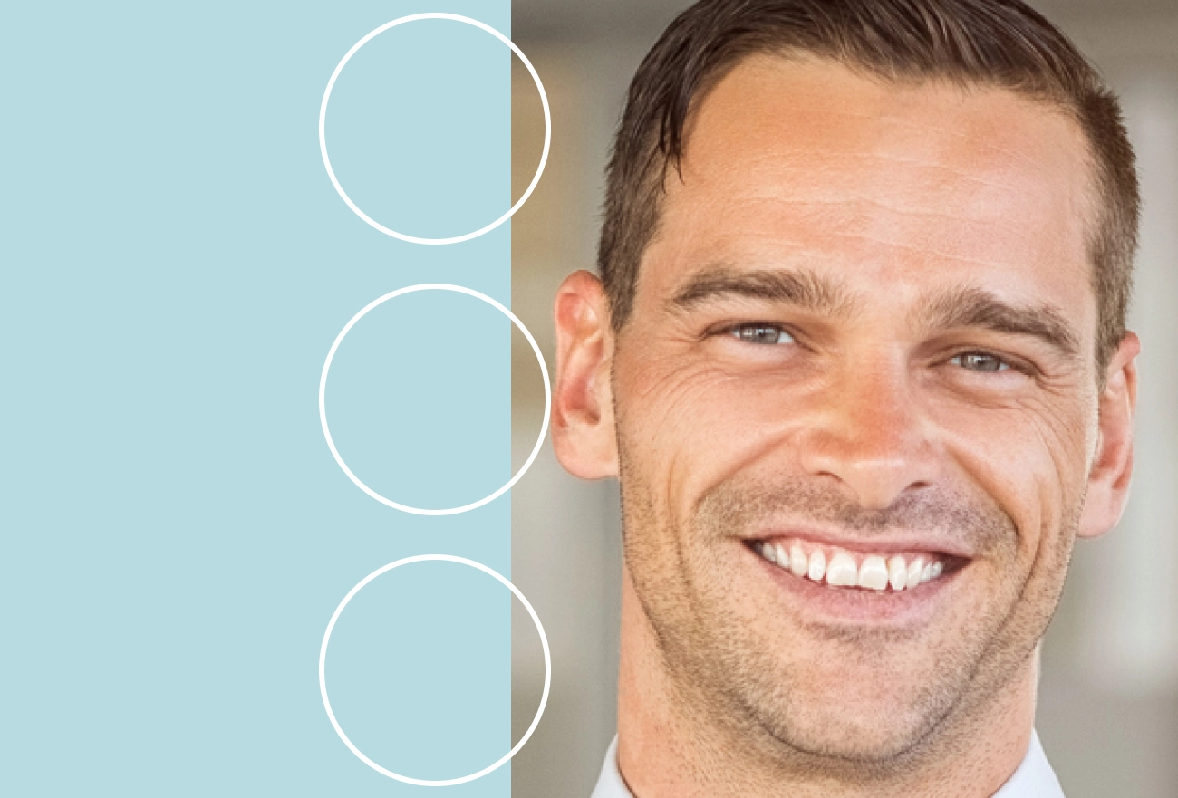 Man smiling next to light blue background with three white circle outlines