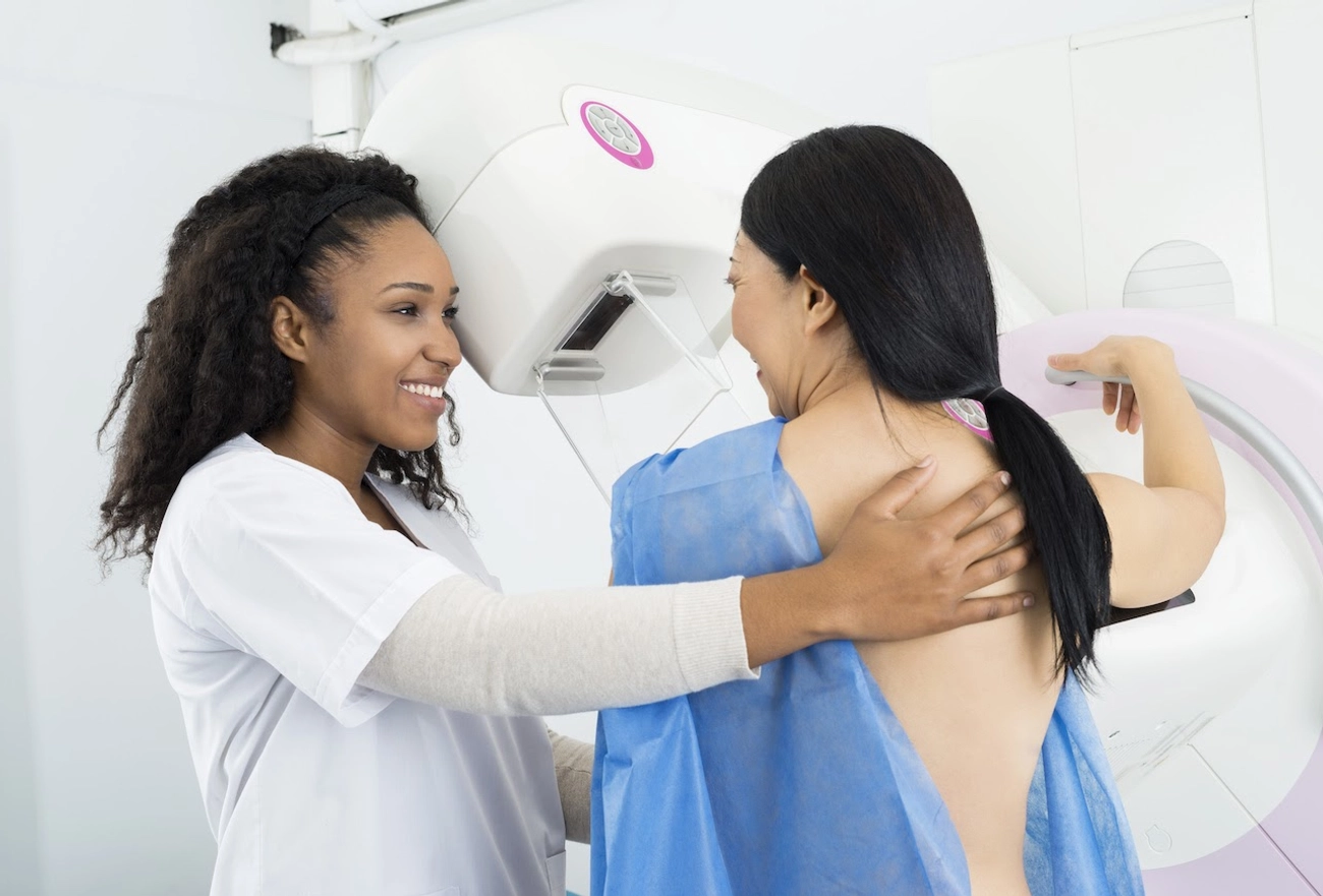Doctor smiling and holding a patient's back before a mammogram screening