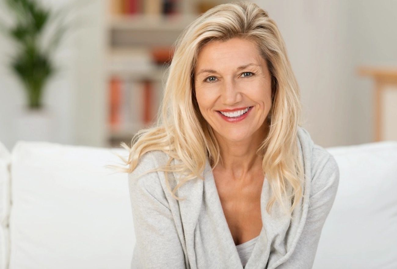 Smiling blonde woman wearing light gray blazer in office setting