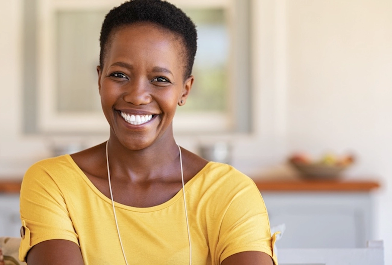 Smiling woman in yellow shirt wearing lanyard in bright office setting