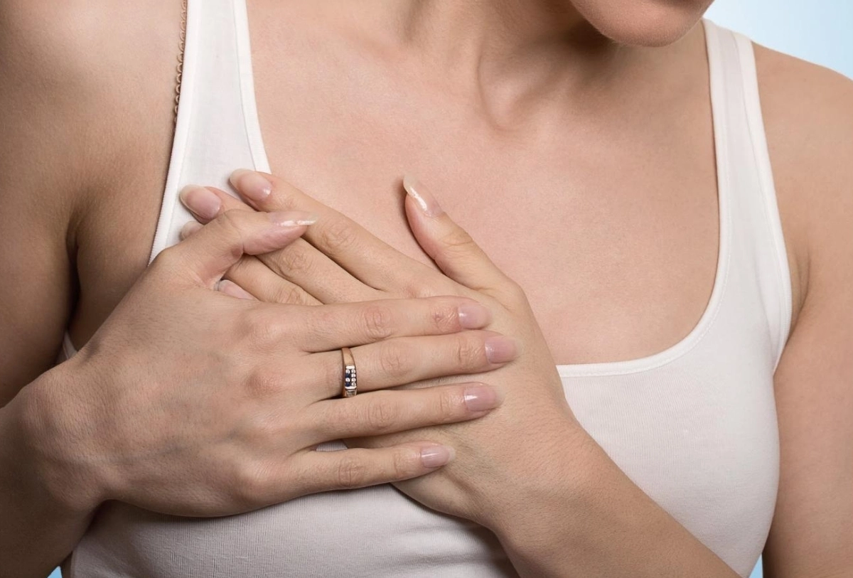 Hands placed on woman's chest during medical breast examination or healthcare consultation