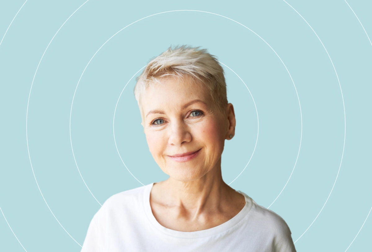 Woman with short blonde hair wearing white shirt smiling against turquoise background with circular design