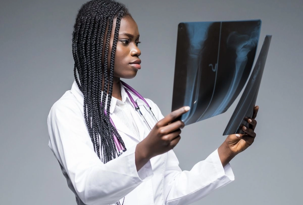 Female doctor examining X-ray images wearing white coat with stethoscope around neck