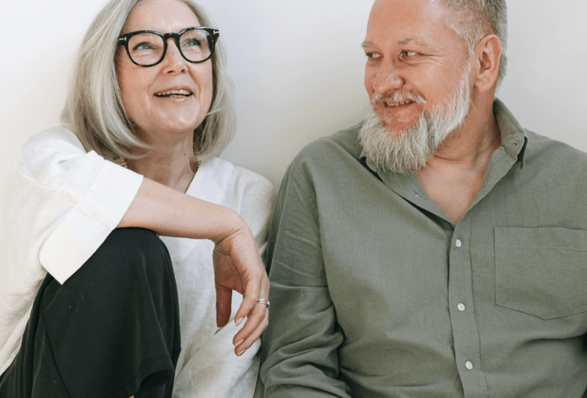 Smiling older couple posing together against white background in casual attire