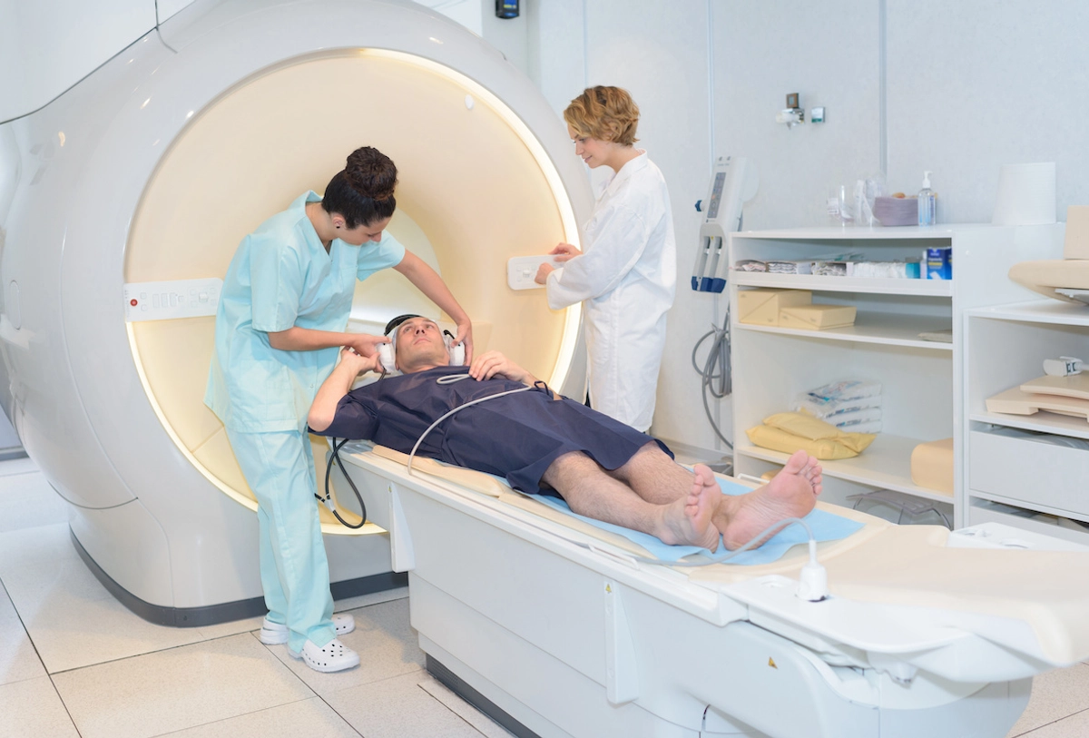Patient undergoing MRI scan with medical technician and healthcare provider in hospital room