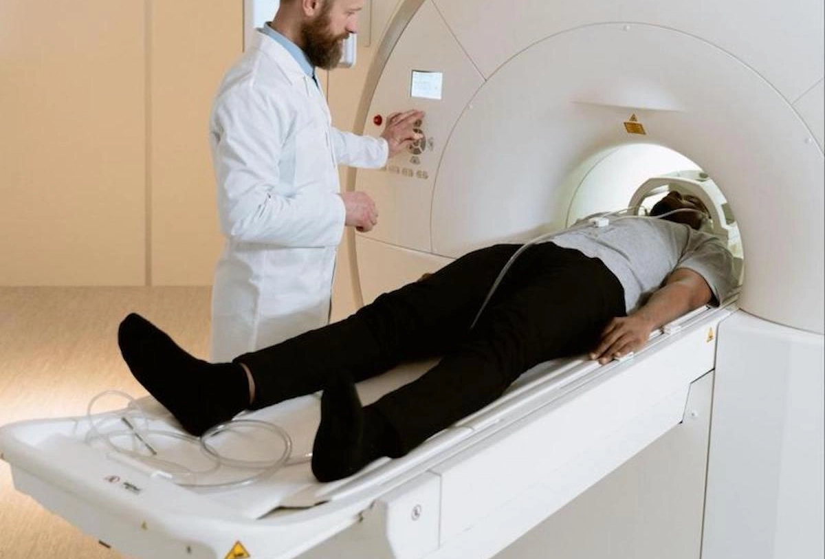 Patient undergoing MRI scan with male technician in white coat operating imaging machine in hospital setting