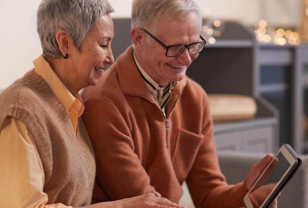 Senior couple smiling while viewing tablet together indoors