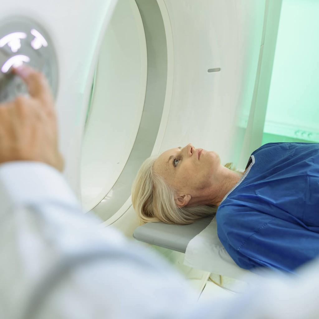 Patient undergoing MRI scan while medical technician operates imaging equipment