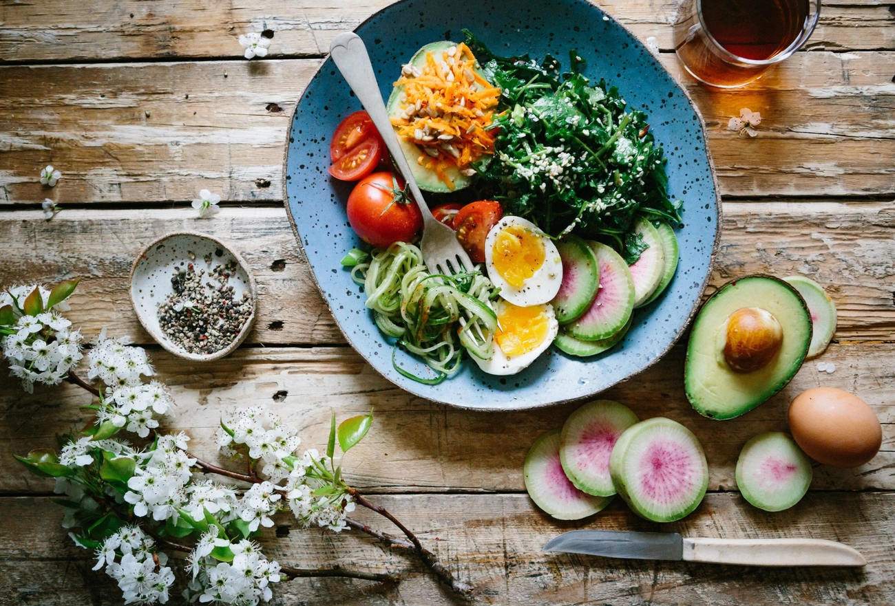 Overhead view of colorful salad bowl with eggs, greens, vegetables, and fresh ingredients