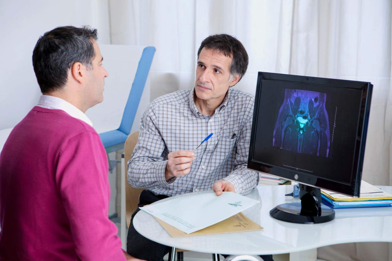 Doctor pointing to thermal medical scan on monitor while consulting with patient in office
