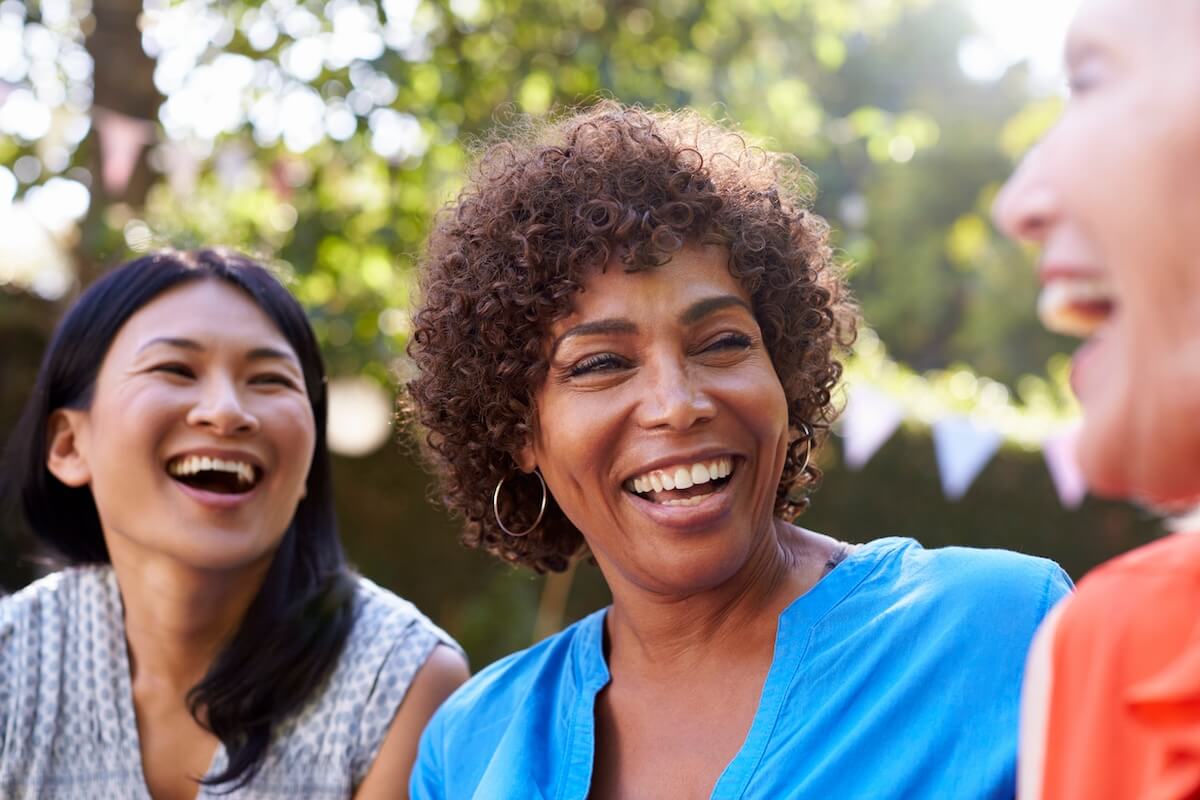 Group of diverse women laughing together outdoors in a park setting