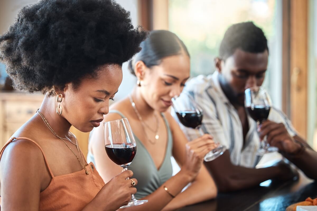 Group of four people enjoying red wine together indoors