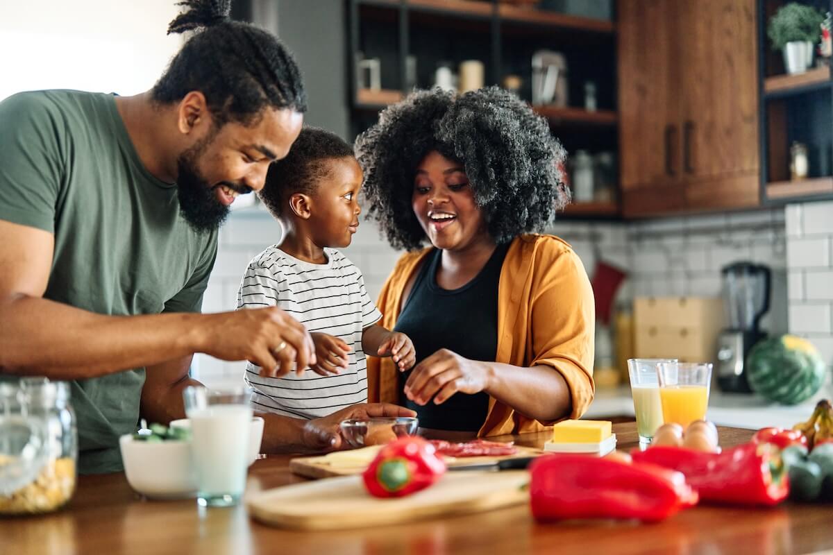 Family preparing healthy meal together in kitchen with fresh vegetables and ingredients on wooden countertop