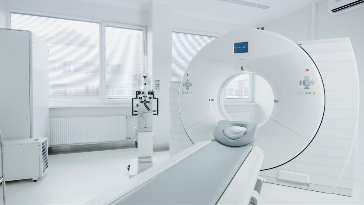 Modern MRI room with large cylindrical scanner, medical equipment, and windows with blinds in clean clinical facility