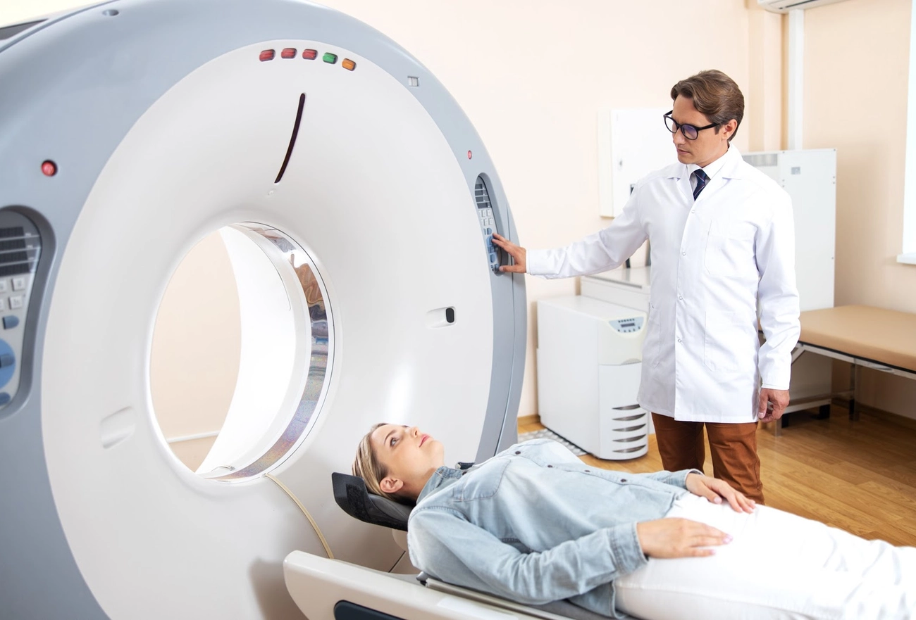 Medical CT scan procedure with patient on examination table and healthcare professional in white coat operating equipment