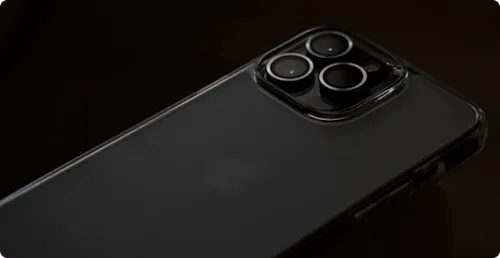 Close-up of the back of a black smartphone with a triple camera setup in a clear protective case on a dark background.