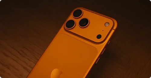 Close-up of the back of a gold smartphone showing three camera lenses and a flash.