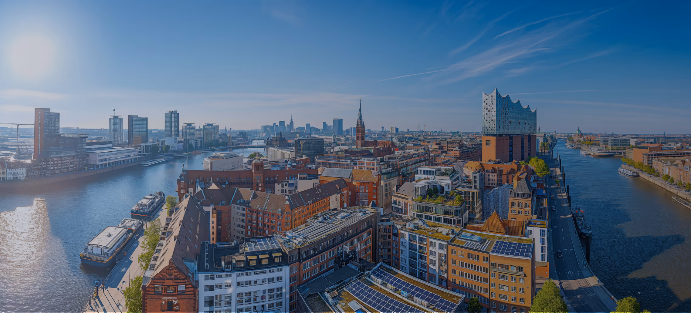 Panoramablick auf Hamburg mit der Elbphilharmonie, Flüssen, Brücken und Stadtgebäuden bei klarem Himmel.