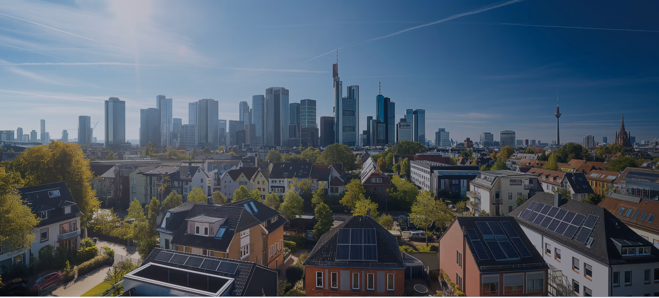Panoramablick auf Frankfurts Skyline mit Hochhäusern und Wohnhäusern mit Solarpanels im Vordergrund an einem sonnigen Tag.