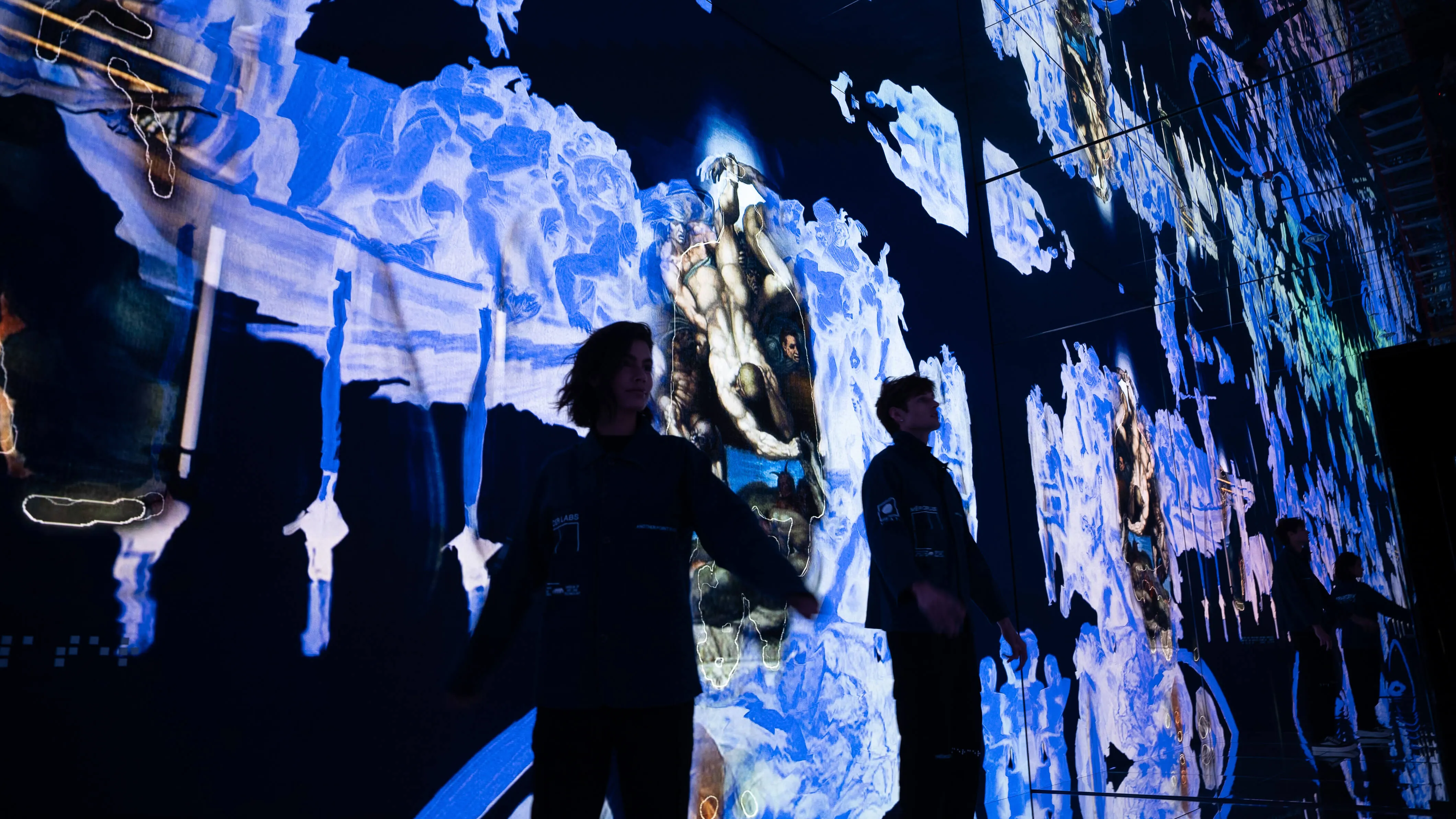 Visitors walk through the mirrored Infinite gallery at Mercer Labs, surrounded by fragmented blue and ochre projections of Michelangelo's Last Judgment, NYC.
