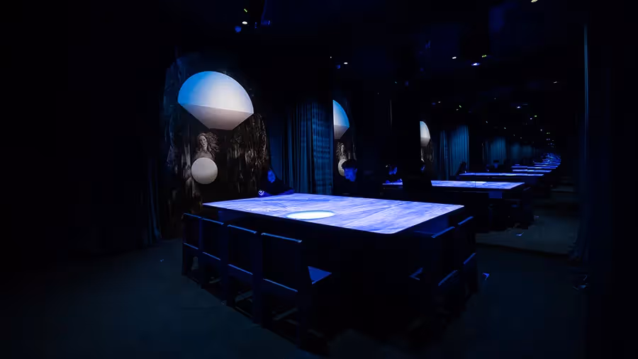 Wide view of multiple illuminated blue tables extending into the mirrored Blue Room gallery at Mercer Labs, Lower Manhattan, with Venus paintings and dome lights repeated down the space.