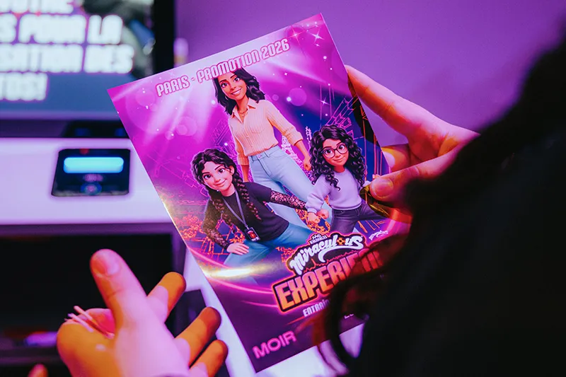 Children watching a holographic projection featuring a red animated character and the word 'SUPER-HÉROS' in a cozy room.