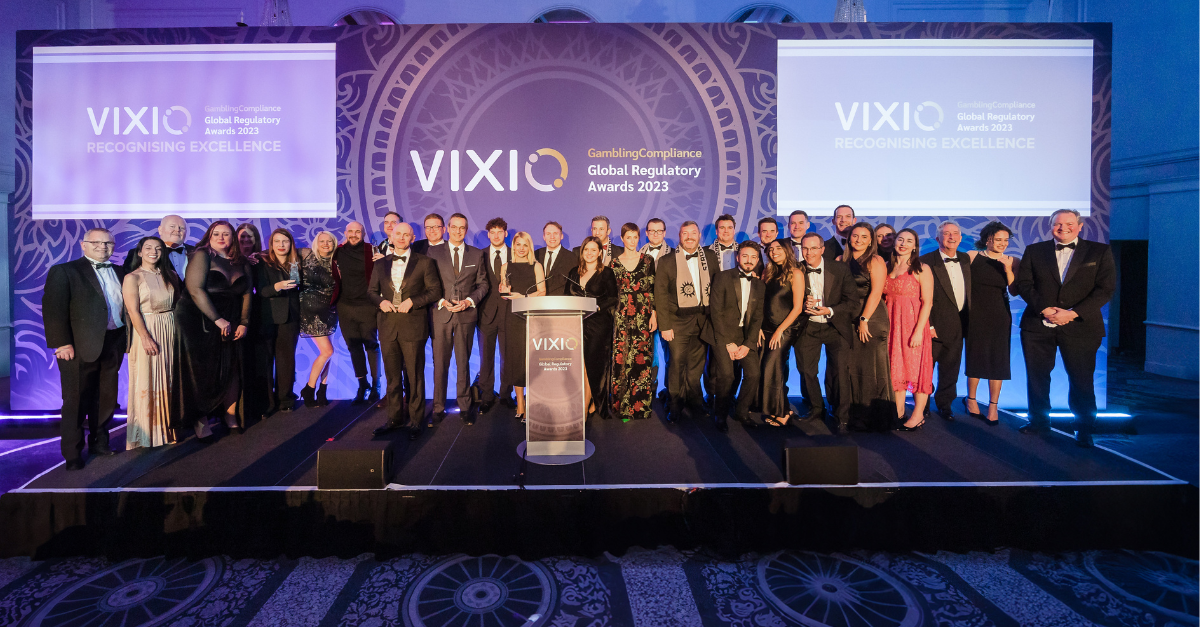 The winners of Vixio's 2023 compliance awards, Global Regulatory Awards, lined up on the purple-lit stage.