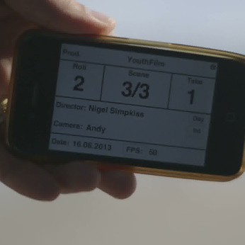 Hand holding a phone screen displaying film production details.