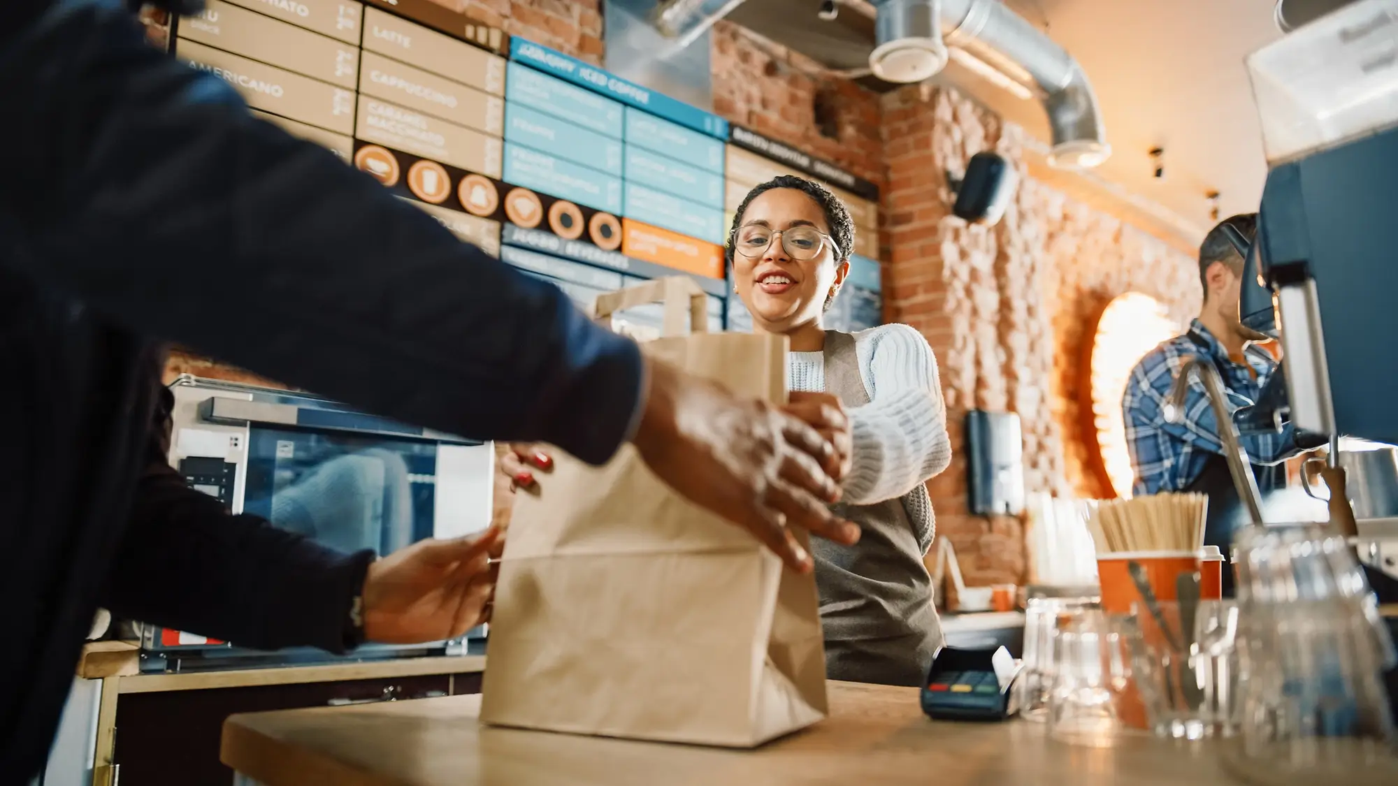 barista handing a to go order to a customer in a trendy cafe
