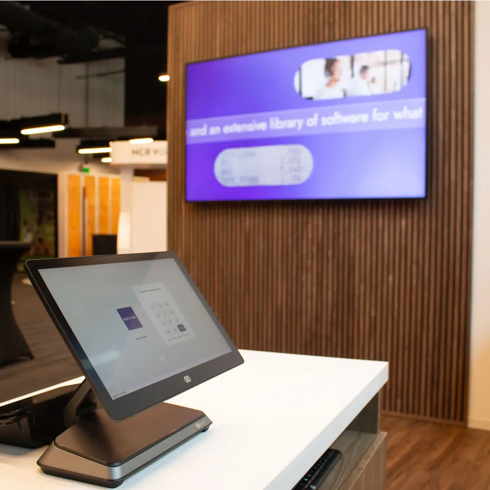 Touchscreen point-of-sale system on white counter in modern office or store environment.