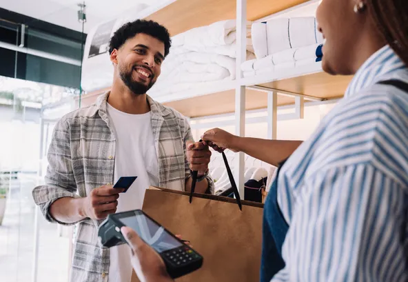 man picking up a to-go order from a restaurant paying with a credit or debit card