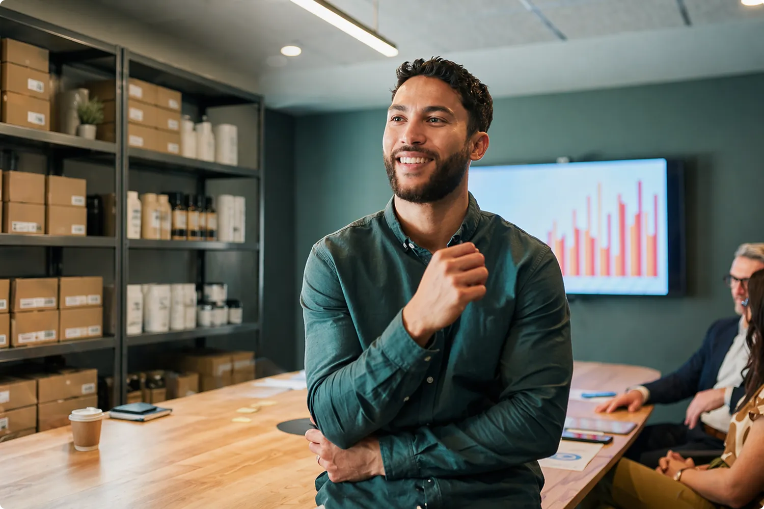 man smiling in a meeting room with a positive growth chart projected on the wall behind him