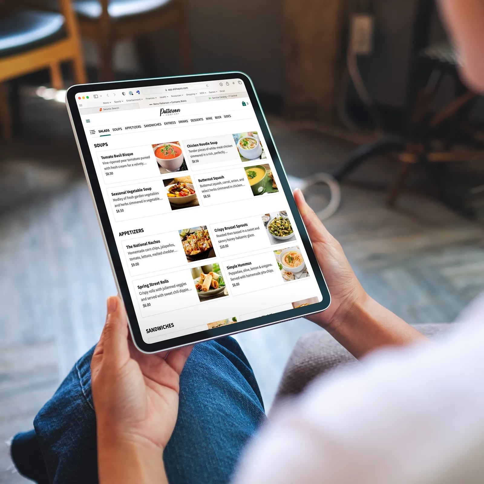 Person holding a tablet showing an online restaurant menu with soups and appetizers.