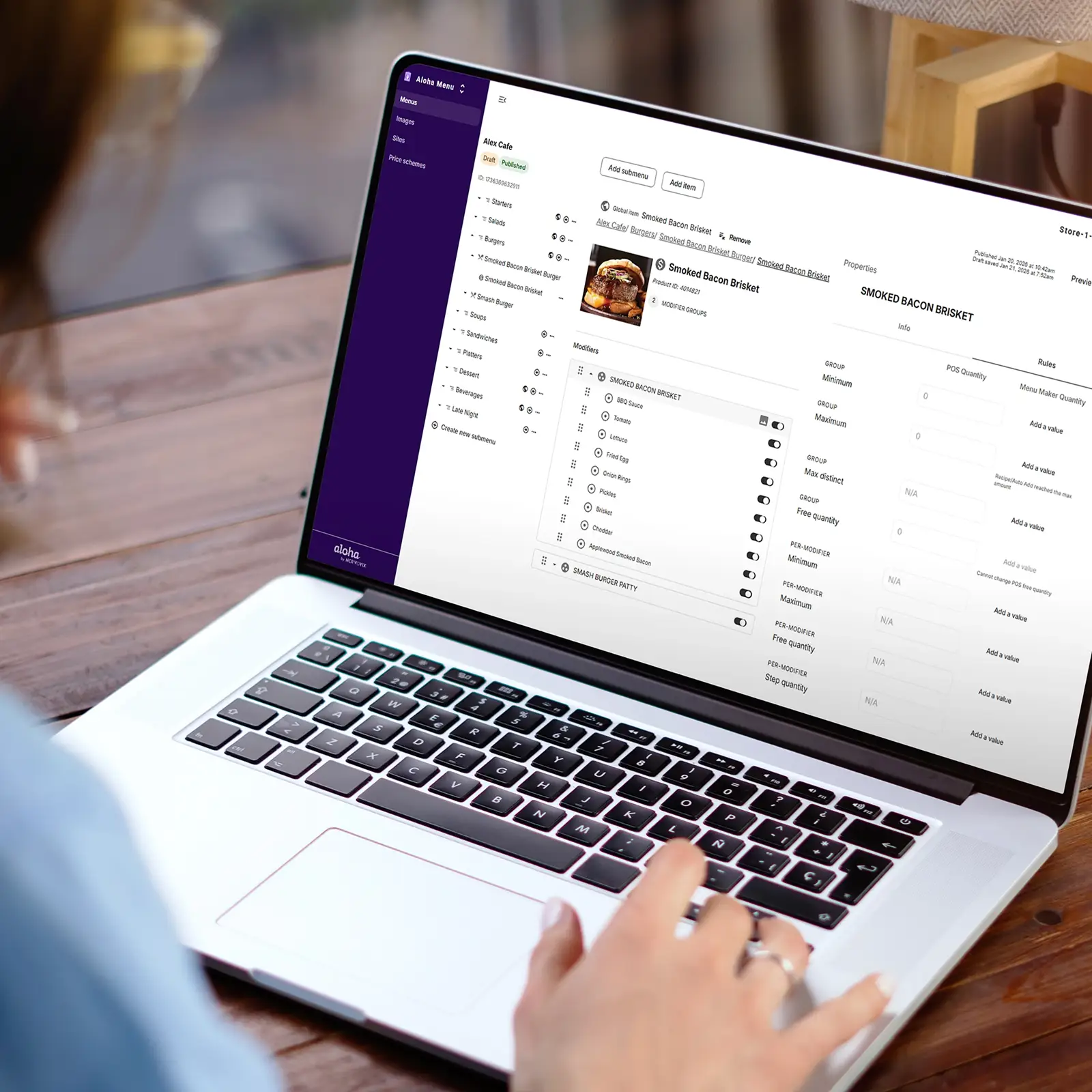 Person using laptop showing menu management interface with Smoked Bacon Brisket item and modifiers.