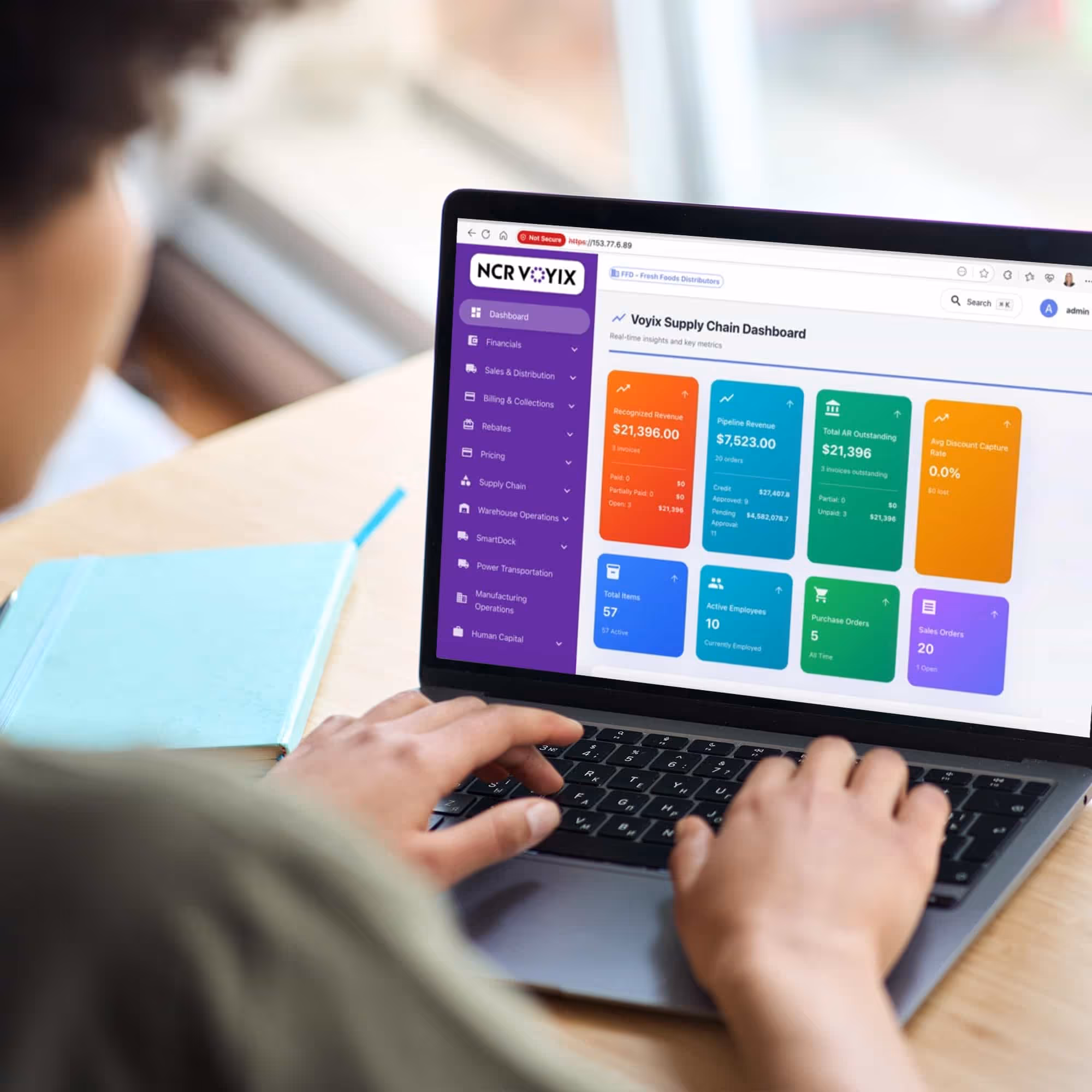 Person using a laptop showing the Voyix Supply Chain Dashboard with financial and operational metrics.
