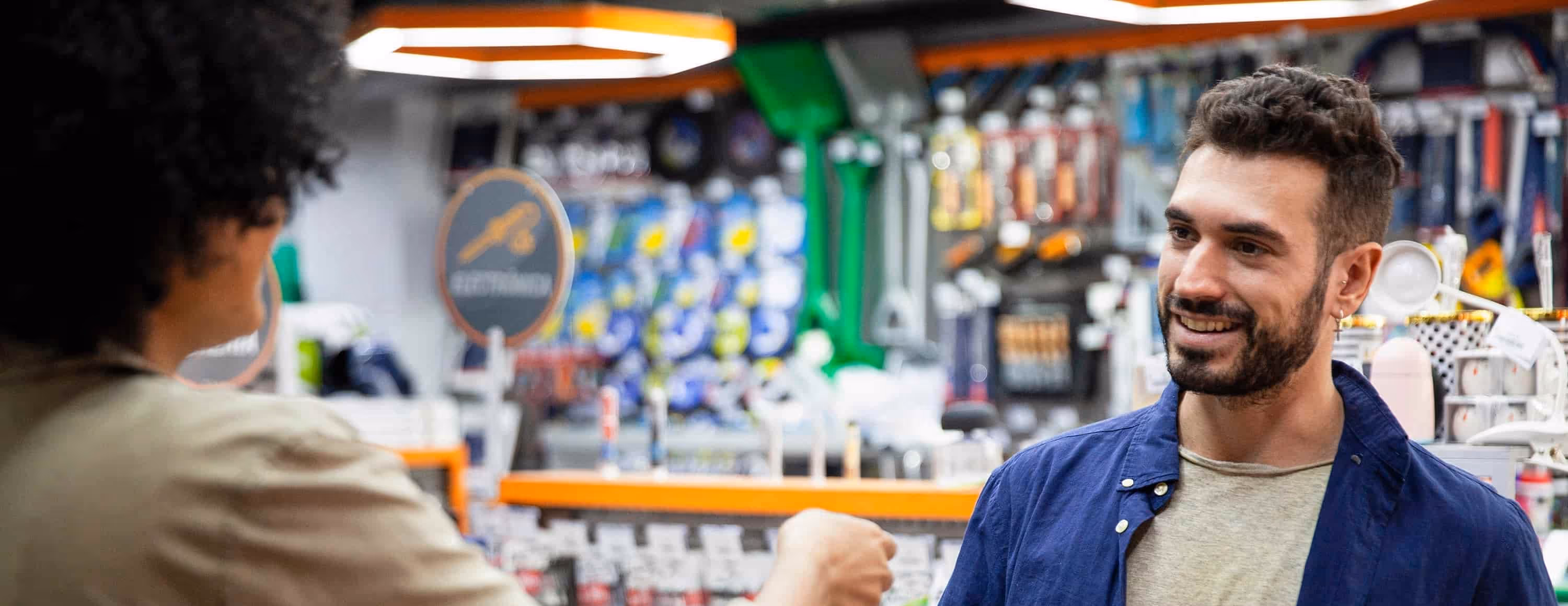 Man with beard smiling and fist bumping someone in a hardware store.