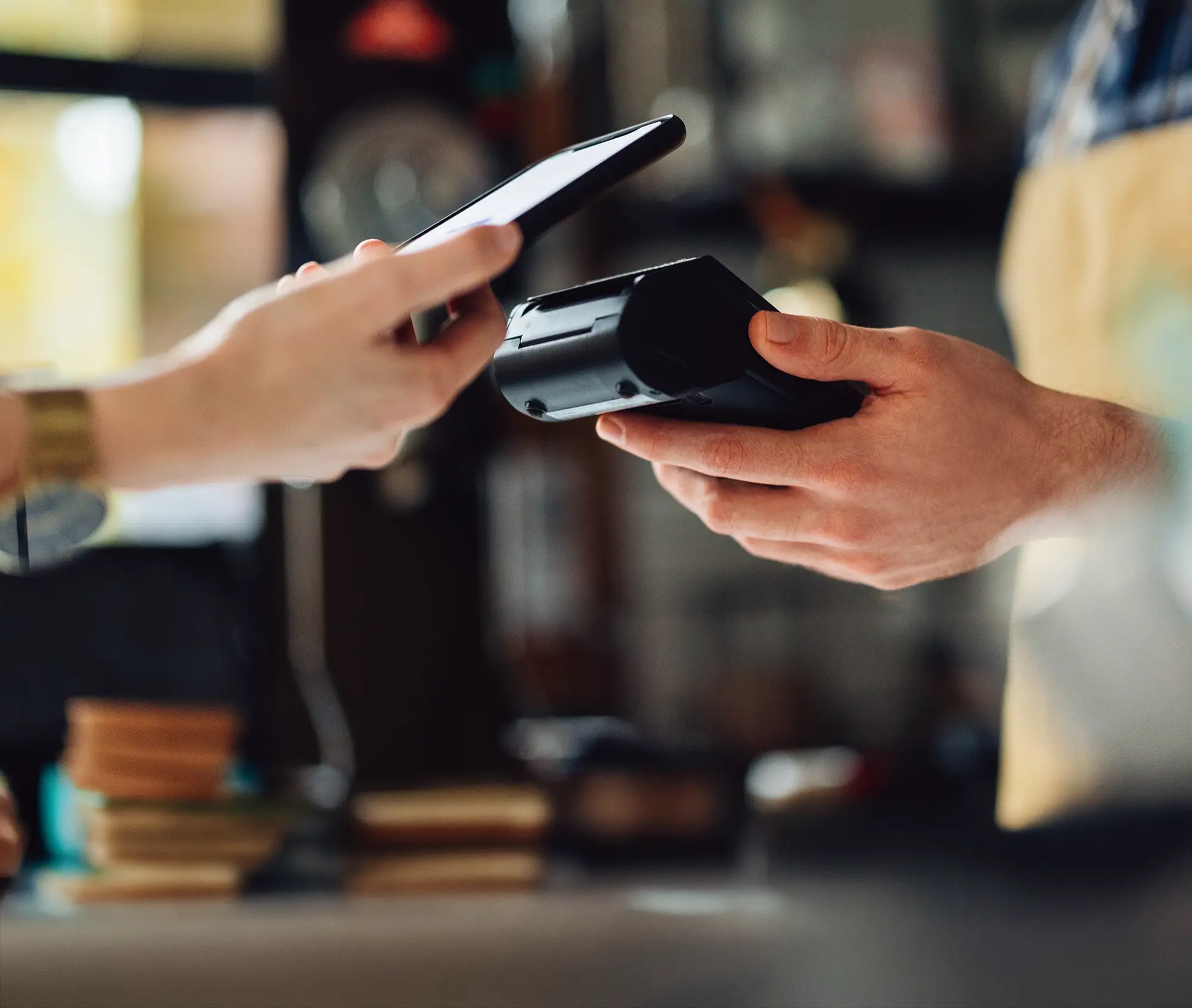 Person making payment with smartphone using contactless payment terminal.