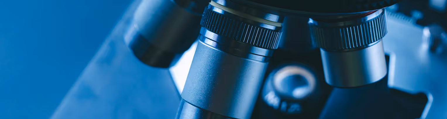 Gros plan sur les objectifs d’un microscope dans une lumière bleue.