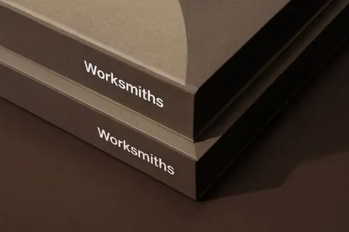 Close-up of two books stacked with the title 'Worksmiths' on a dark surface.