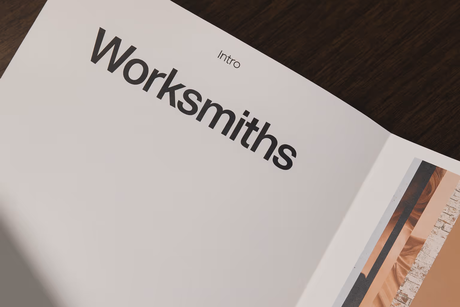 Open magazine page with the word 'Worksmiths' in large font and 'Intro' above it on a dark wooden table.